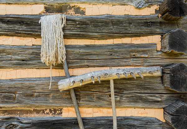 Old rake and mop against log cabin by Steve Heap