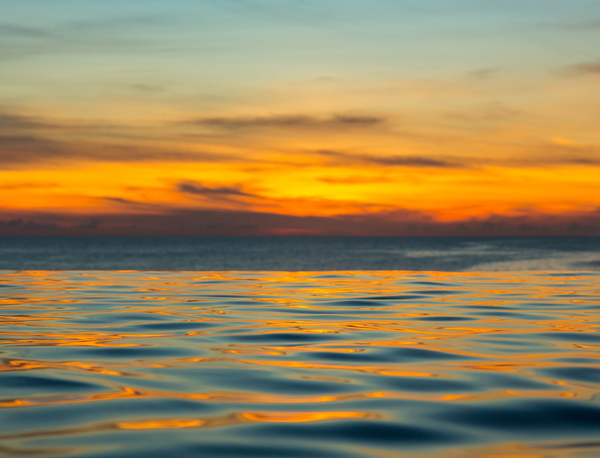 Infinity edge pool with sea underneath sunset by Steve Heap