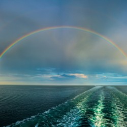 Dramatic double rainbow over wake of ship