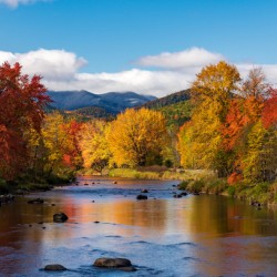 Saranac river flows through multi-colored fall landscape in Adir