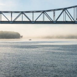 Fisherman fishing in Mississippi river on misty autumn morning