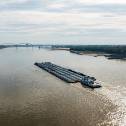Large barge boat sails under Memphis bridge in October 2023