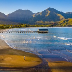 Aerial drone shot of man on the sand of Hanalei beach 