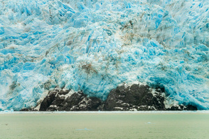 Amalia Glacier towers over large rocks and trees in Patagonia