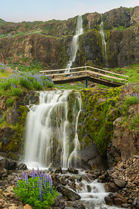 Budareyrarfoss waterfall cascades down the mountain by the port 