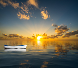 White rowing boat adrift on open ocean drifting to sunset