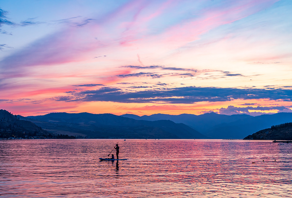 Sunset over Lake Chelan with silhouette of couple paddling on pa by Steve Heap