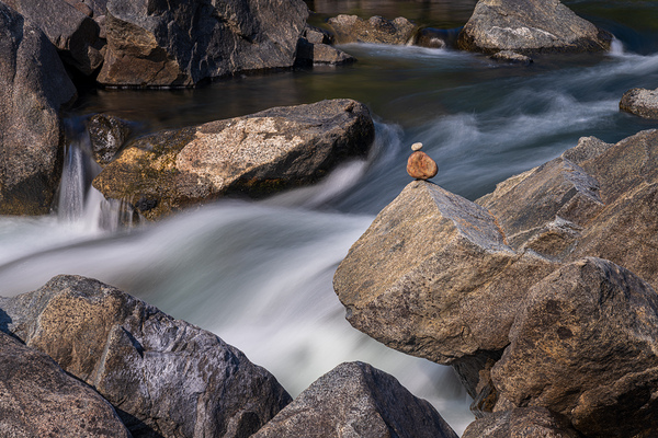 Pebbles balanced on rocks in raging river illustrating resilienc by Steve Heap
