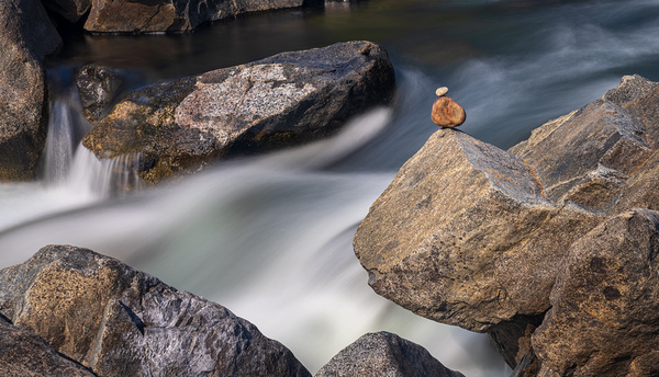 Pebbles balanced on rocks in raging river illustrating resilienc by Steve Heap