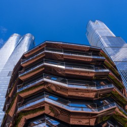 Reflective surface of the Vessel with a skyscraper behind with c