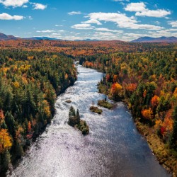 Saranac river flows through multi-colored fall landscape in Adir