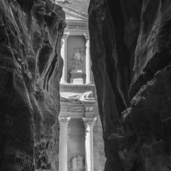 Monochrome Petra Treasury building facade seen through narrow go