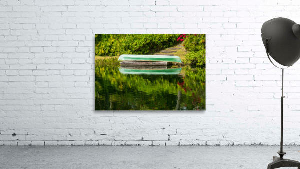 Green canoe on dock reflecting into calm lake or pond in garden Wall Preview
