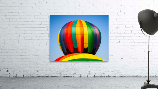 Colorful hot air balloon rising above another with blue sky Wall Preview