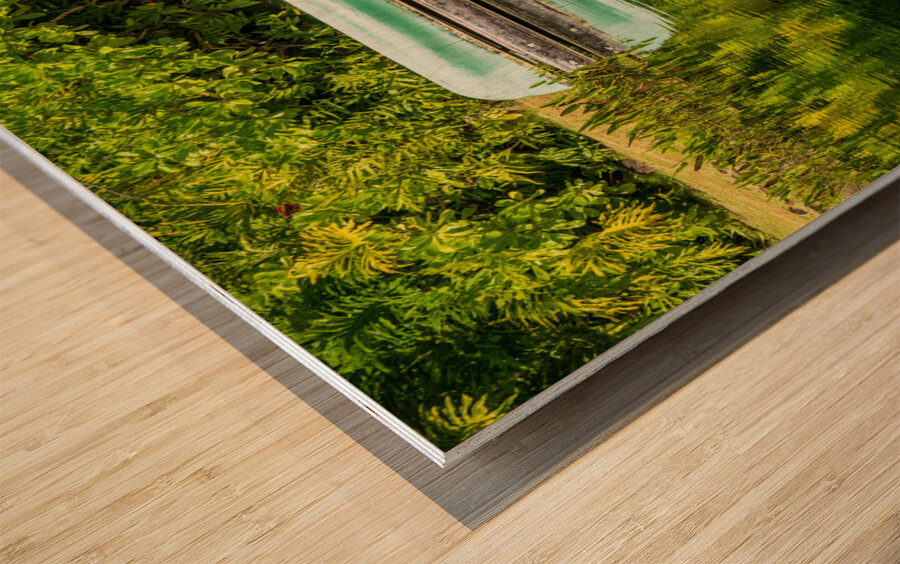 Green canoe on dock reflecting into calm lake or pond in garden Wood print